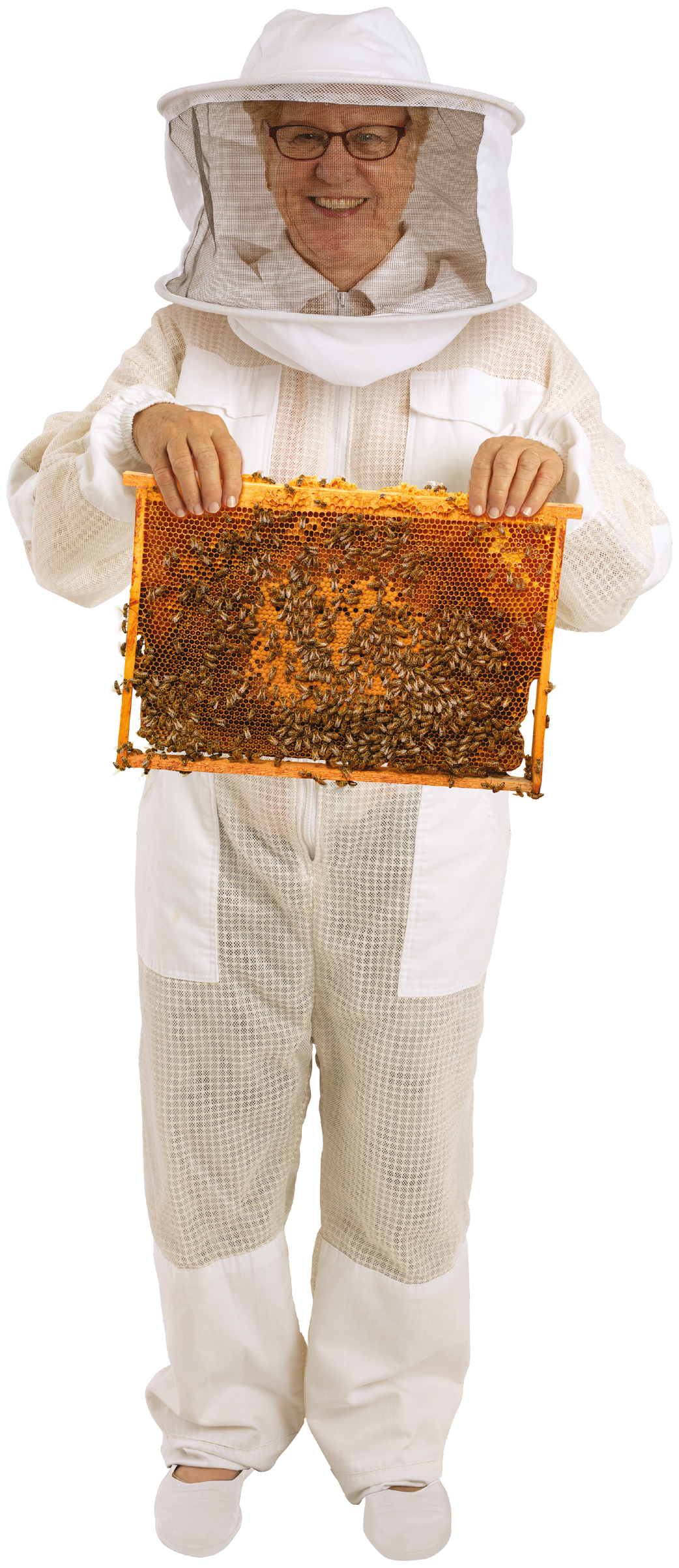 Jill Richards in a beekeeping suit holding up a honeycomb frame covered in bees, full figure