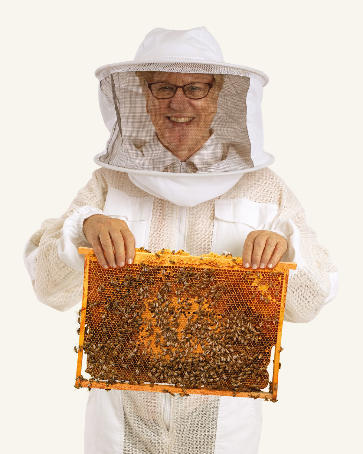 Jill Richards in a beekeeping suit holding up a honeycomb frame covered in bees